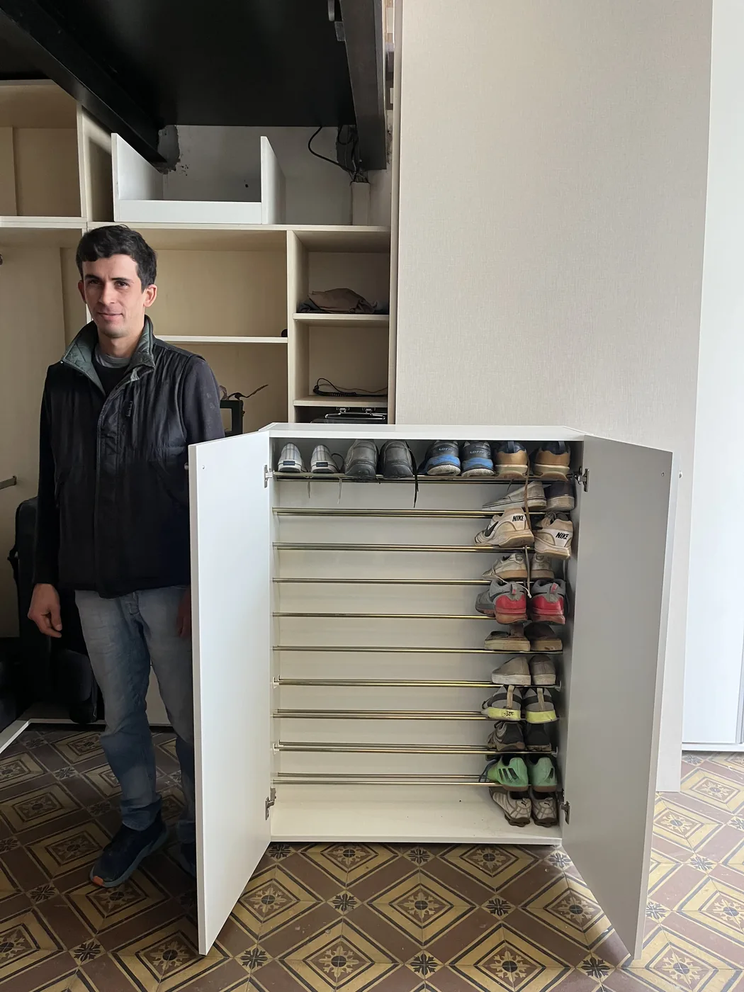 Zapatero blanco de dos puertas abierto en el local, con una persona al lado que da idea del tamaño